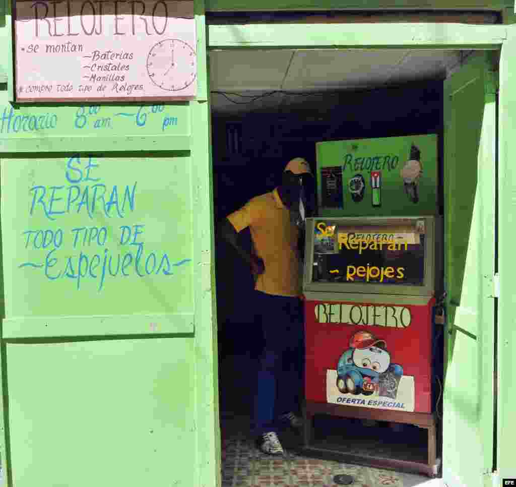 Un hombre entra al local de un cuentapropista técnico en reparación relojes.