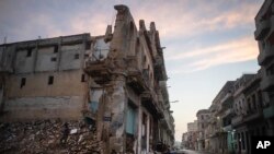 Edificios ruinosos y derrumbados bordean la calle San Lázaro, donde un hombre, a la izquierda, recoge ladrillos en el centro de La Habana (10 de octubre de 2023). (AP/Ramón Espinosa).