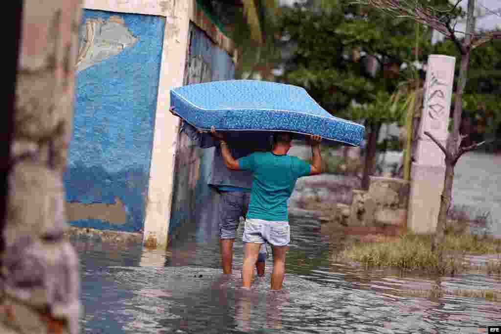 Dos hombres trasladan un colchón por una calle inundada por las penetraciones del mar hoy, sábado 23 de enero de 2016, en La Habana (Cuba). EFE/Alejandro Ernesto