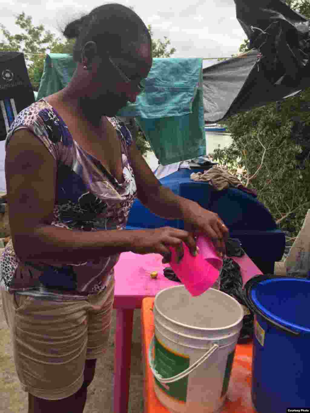 Una mujer friega unas vasijas de plástico en su albergue de la localidad colombiana de Turbo. Colombia. Foto: R. Quintana.