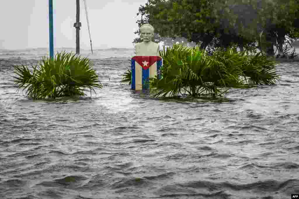 Una estatua de Martí y una bandera cubana en medio de las inundaciones que afectaron este miércoles a la localidad ee Guanímar, en Artemisa, Cuba. (Yamil Lage/AFP)