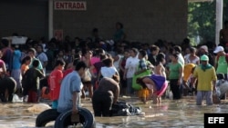 Personas cargan productos saqueados a tiendas hoy en el puerto de Acapulco (México), tras el paso del huracán Manuel