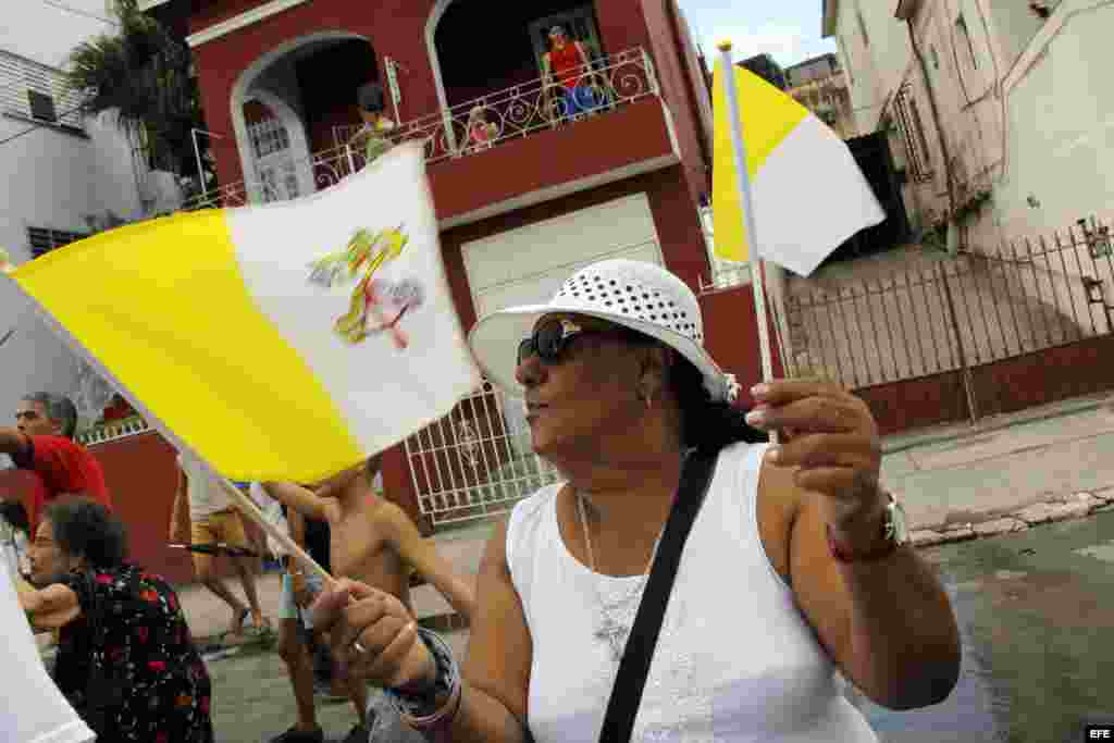 Una mujer agita las banderas de Cuba y el Vaticano, a la llegada del Papa a la isla.