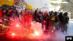 Integrantes de la Guardia Nacional Bolivariana (GNB) se protegen durante enfrentamientos con manifestantes.