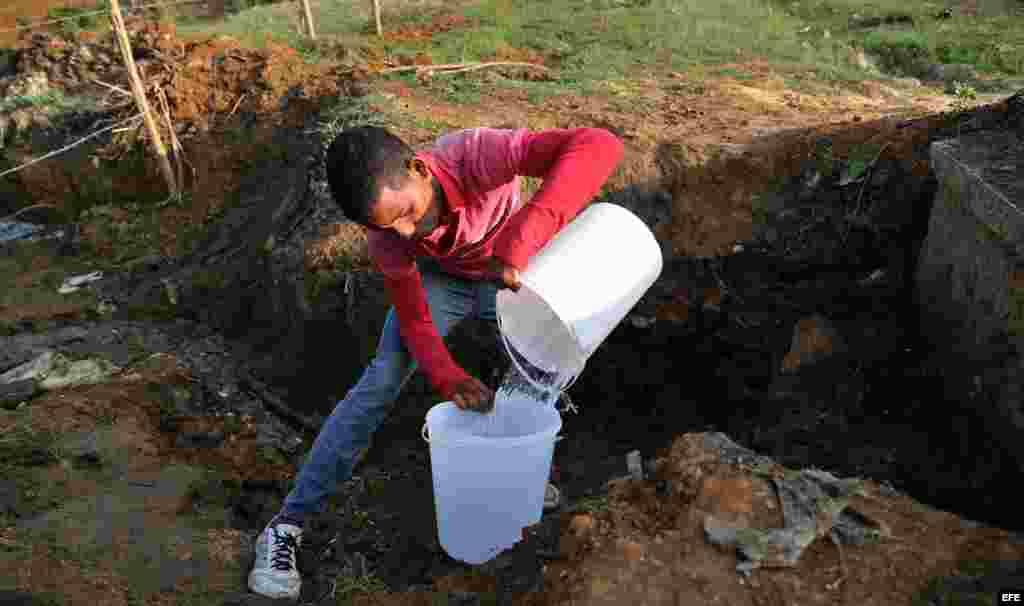 Un hombre llena dos cubos de agua en un salidero de una tubería en la provincia de Ciego de Ávila.