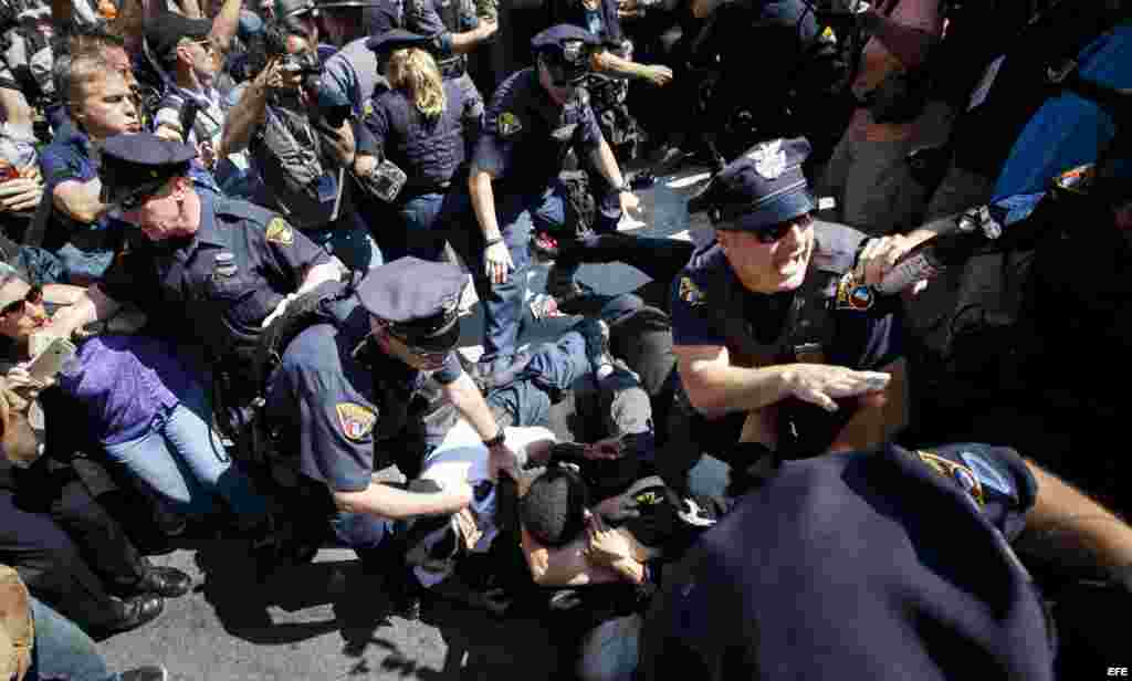 Un grupo de manifestantes es detenido por la policía luego de quemar una bandera de EE.UU. cerca a la entrada a Quicken Loans Arena, sitio donde se realiza la Convención Nacional Republicana.