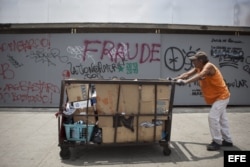 Un hombre empuja un carrito frente a un muro con una pintada en donde se lee "fraude" hoy, miércoles 17 de abril de 2013, escrito como una protesta contra el presidente venezolano, Nicolás Maduro y el resultado electoral que le dio como vencedor en Caraca