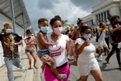 Una mujer con un niño en brazos marcha frente al Capitolio de La Habana durante una manifestación contra el presidente cubano Miguel Díaz-Canel en La Habana, el 11 de julio de 2021.