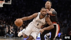 El jugador Deron Williams (C) de los Brooklyn Nets disputa el balón con Damian Lillard (d) de los Portland Trail Blazers durante el primer cuarto de su partido de la NBA en el Barclays Center en Brooklyn (Estados Unidos). 