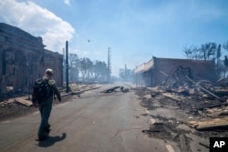 Un hombre pasa junto a los restos del incendio forestal, el miércoles 9 de agosto de 2023, en Lahaina, Hawai. (Tiffany Kidder Winn vía AP)