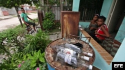 Varias personas permanecen junto a botellas de ron vacías en una vivienda del barrio Alturas de la Lisa en La Habana donde hace pocos días se produjo un caso de intoxicación con alcohol metílico o "de madera" comercializado ilegalmente.