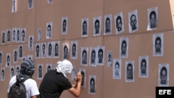 Estudiantes pegan retratos de los 43 jóvenes desaparecidos durante la noche del 26 de septiembre, tras un ataque perpetrado por policías municipales.