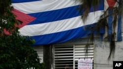 En esta fotografía de archivo, Yunior García, dramaturgo y uno de los organizadores de una marcha de protesta, junto a un cartel que dice "Mi casa está bloqueada", que colocó en una ventana de su casa, en La Habana el 14 de noviembre de 2021. (AP Foto/Ramón Espinosa, Archivo)